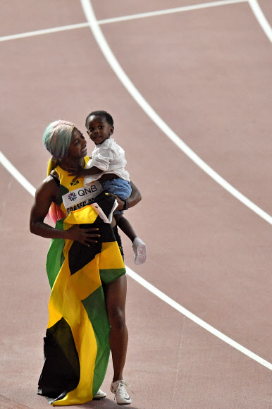 자메이카 육상 선수 셸리 앤 프레이저-프라이스가 29일(현지시간) 카타르 도하에서 열린 세계육상선수권대회 여자 100m 결선에서 금메달을 따낸 뒤 아들 지온과 기뻐하고 있다. 이날 프레이저-프라이스는 10초 71로 올 시즌 최고 기록을 세웠다. AP 연합뉴스