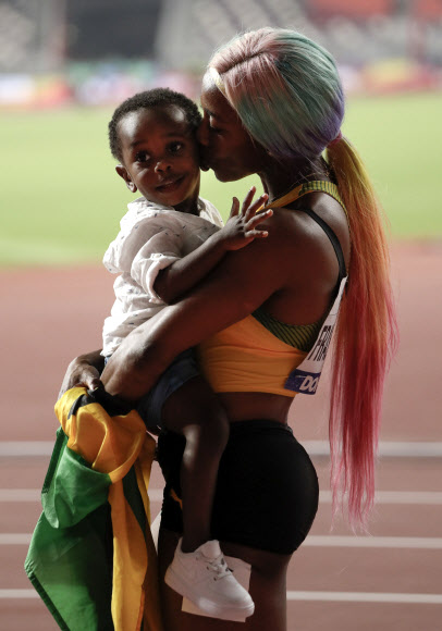 자메이카 육상 선수 셸리 앤 프레이저-프라이스가 29일(현지시간) 카타르 도하에서 열린 세계육상선수권대회 여자 100m 결선에서 금메달을 따낸 뒤 아들 지온과 기뻐하고 있다. 이날 프레이저-프라이스는 10초 71로 올 시즌 최고 기록을 세웠다. AP 연합뉴스