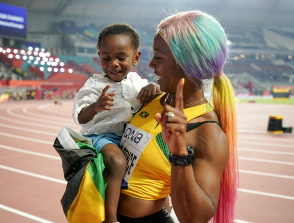 자메이카 육상 선수 셸리 앤 프레이저-프라이스가 29일(현지시간) 카타르 도하에서 열린 세계육상선수권대회 여자 100m 결선에서 금메달을 따낸 뒤 아들 지온과 기뻐하고 있다. 이날 프레이저-프라이스는 10초 71로 올 시즌 최고 기록을 세웠다. AP 연합뉴스