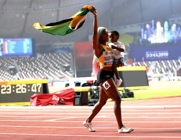 자메이카 육상 선수 셸리 앤 프레이저-프라이스가 29일(현지시간) 카타르 도하에서 열린 세계육상선수권대회 여자 100m 결선에서 금메달을 따낸 뒤 아들 지온과 기뻐하고 있다. 이날 프레이저-프라이스는 10초 71로 올 시즌 최고 기록을 세웠다. AP 연합뉴스