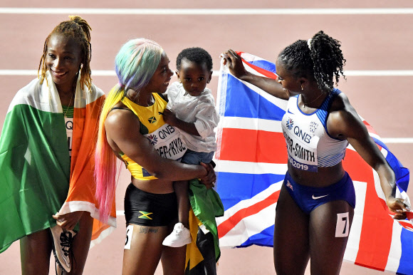 자메이카 육상 선수 셸리 앤 프레이저-프라이스(가운데)가 29일(현지시간) 카타르 도하에서 열린 세계육상선수권대회 여자 100m 결선에서 금메달을 따낸 뒤 아들 지온과 기뻐하고 있다. 이날 프레이저-프라이스는 10초 71로 올 시즌 최고 기록을 세웠다. AP 연합뉴스