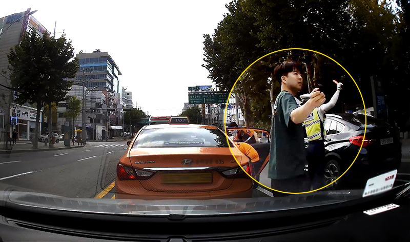 박상현씨가 지난 5일 오전 서울 서초구 서울고교 사거리 인근 도로에서 택시 안에 응급환자가 있는 것을 목격하고 119에 신고했다. 사진은 박씨가 수신호로 차량들의 서행을 유도하는 등 추가 사고 예방에 힘쓰고 있는 모습.