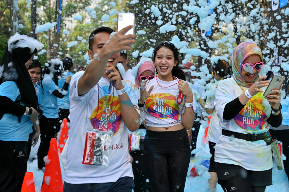 사람들이 13일(현지시간) 인도네시아 자카르타에서 열린 ‘5km 컬러 런(a five-kilometre Colour Run)’에 참가해 즐거운 시간을 보내고 있다. 수천 명이 달리기에 참여해 건강한 생활방식을 고취하는 데 집중했다. AFP 연합뉴스