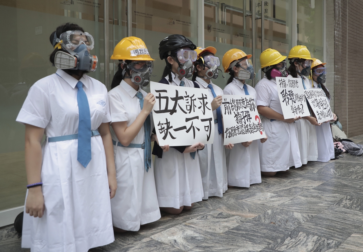 홍콩에서 방독면과 헬멧을 쓴 학생들이 9월 2일(현지시간) 무릎을 꿇은 채 ‘5대 요구, 하나도 빠지면 안된다’는 글귀 등을 내세우며 시위하고 있다.  AP 연합뉴스