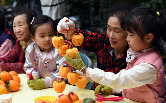 24일 서울 광진구 구립수호천사어린이집에서 열린 ‘3대가 나누는 핑크 바이러스 곶감 사랑 행사’에서 어르신들과 어린이들이 곶감을 만들고 있다. 2019. 10. 24. 박윤슬 기자 seul@seoul.co.kr