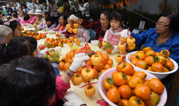 24일 서울 광진구 구립수호천사어린이집에서 열린 ‘3대가 나누는 핑크 바이러스 곶감 사랑 행사’에서 어르신들과 어린이들이 곶감을 만들고 있다. 2019. 10. 24. 박윤슬 기자 seul@seoul.co.kr