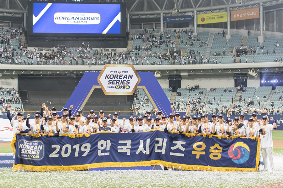두산 베어스 선수들이 우승 현수막을 펼치고 기념 촬영을 하고 있다.