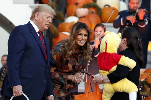 도널드 트럼프(왼쪽) 대통령과 멜라니아 트럼프 영부인이 28일(현지시간) 할로윈을 위해 장식된 백악관의 남쪽 잔디밭에서 할로윈 행사 중에 아이들에게 사탕을 나눠주고 있다. AP 연합뉴스