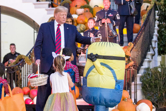 도널드 트럼프(왼쪽) 대통령과 멜라니아 트럼프 영부인이 28일(현지시간) 할로윈을 위해 장식된 백악관의 남쪽 잔디밭에서 할로윈 행사 중에 아이들에게 사탕을 나눠주고 있다. AP 연합뉴스