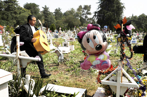 한 음악가가 1일(현지시간) 멕시코 시티의 산 이시드로 묘지에서 ‘죽은자의 날’ 축제 중 어린이 구역을 걷고 있다. AP 연합뉴스