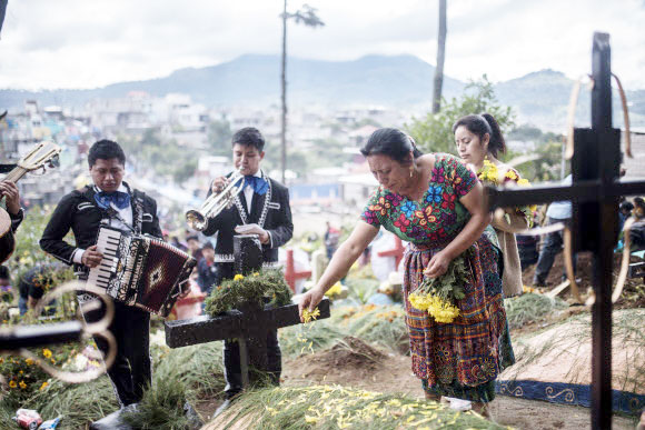 한 여성이 1일(현지시간) 과테말라 섬팡고에서 열린 ‘죽은자의 날’ 동안 아버지의 무덤을 꽃으로 꾸미고 있다. AP 연합뉴스