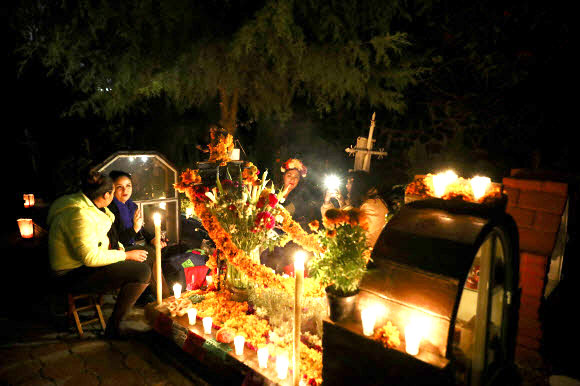 친척들이 1일(현지시간) 멕시코 시티의 로스 레이예스 공동묘지에서 ‘죽은 자의 날’ 기념 축제 중 사랑하는 사람의 무덤 옆에서 밤을 보내고 있다. AP 연합뉴스