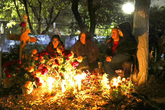 친척들이 1일(현지시간) 멕시코 시티의 로스 레이예스 공동묘지에서 ‘죽은 자의 날’ 기념 축제 중 사랑하는 사람의 무덤 옆에서 밤을 보내고 있다. AP 연합뉴스