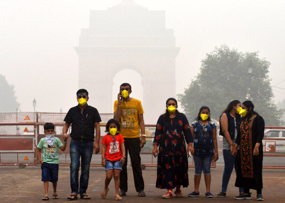 지난 3일 인도 뉴델리에서 일가족이 도심에서 노란색 마스크를 쓰고 있다.