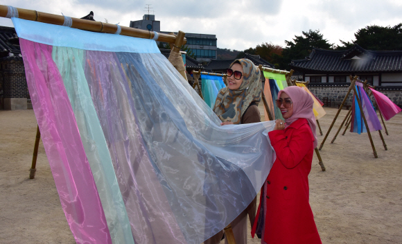5일 서울 중구 남산골한옥마을에서 열리고 있는 ‘한옥, 걸다’ 전시에서 관람객 및 관광객들이한옥마을 마당에 펼쳐지는 ‘한복 치마’를 주제의 이승주 한복 디자이너의 전시를 둘러보고 있다. 2019.11.5.    이종원 선임기자 jongwon@seoul.co.kr