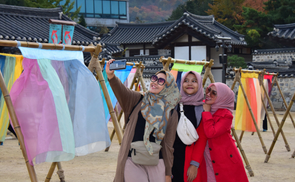 5일 서울 중구 남산골한옥마을에서 열리고 있는 ‘한옥, 걸다’ 전시에서 관람객 및 관광객들이한옥마을 마당에 펼쳐지는 ‘한복 치마’를 주제의 이승주 한복 디자이너의 전시를 배경으로 사진촬영을 하고 있다. 2019.11.5.    이종원 선임기자 jongwon@seoul.co.kr
