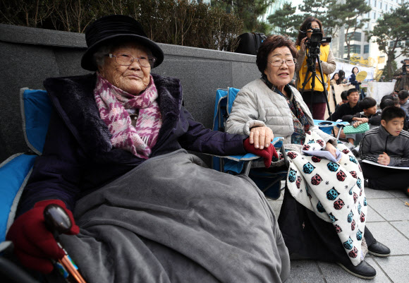 6일 서울 종로구 중학동 옛 일본대사관 앞에서 열린 ‘일본군 성노예제 문제 해결을 위한 제1412차 정기 수요시위’에서 생일을 맞은 이옥선(왼쪽부터), 이용수 할머니가 손을 잡고 있다. 2019.11.6  연합뉴스
