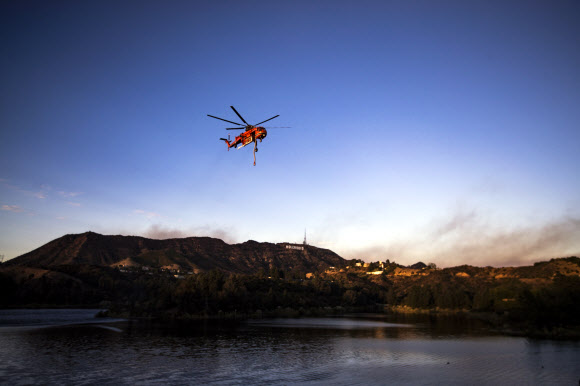 소방 헬기가 9일(현지시간) 미국 캘리포니아주 로스앤젤레스의 할리우드 사인 뒤에서 발생한 바햄 화재를 진압하기 위해 저수지에서 물을 보충한 후 이륙하고 있다. 최근 언론 보도에 따르면 화재는 25에이커를 태웠고 현재는 진압되고 있다. EPA 연합뉴스