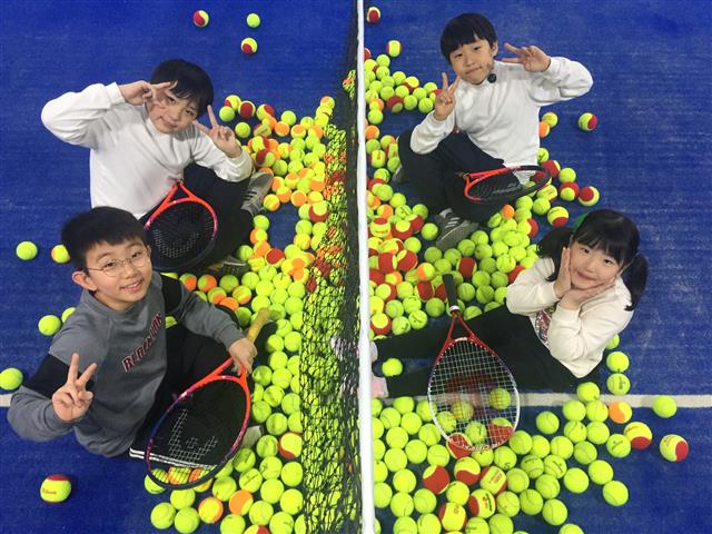 매직 테니스를 배우고 있는 초등학생 4명이 지난 13일 경기 의정부 민락동에 있는 한 실내 테니스 아카데미에서 레드볼과 오렌지볼, 그린볼 등 전용 감압구가 쌓여 있는 코트 바닥에 앉아 놀이하듯 즐거운 시간을 보내고 있다.