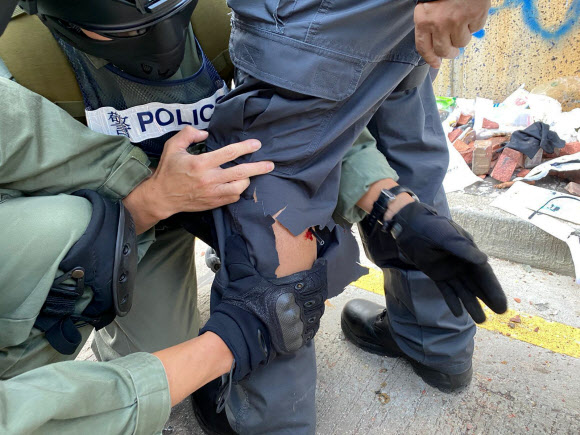 17일(현지시간) 홍콩 폴리테크닉대학 시위 현장에서 경찰관 한 명이 날아온 화살에 왼쪽 종아리를 맞아 부상을 당했다. AP 연합뉴스 