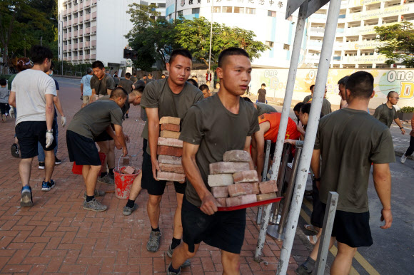 지난 16일 홍콩 주둔 중국 인민해방군 병사 수십명이 지난 6월 시위 발생 이후 처음으로 기지 밖으로 나와 시위대가 차량 통행을 방해하고자 도로에 놓아둔 벽돌을 치우고 있다. 홍콩 AFP 연합뉴스