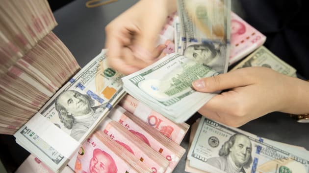 중국 동부 장쑤성 난퉁에 있는 한 은행 직원이 지난 8월 26일 100위안화 지폐 다발 뭉치를 두고 100달러 지페를 세고 있다. 난퉁 AFP 연합뉴스