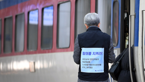 19일 서울 용산구 서울역에서 한 직원이 노조의 요구사항이 적힌 조끼를 입고 일을 하고 있다. 지난 15일부터 열차 출발을 지연시키는 ‘준법투쟁’에 들어간 전국철도노동조합은 4조 2교대 근무제 도입을 위한 인력 4천명 충원 등을 요구하며 오는 20일부터 무기한 총파업에 들어갈 예정이다. 2019. 11. 19 박윤슬 기자 seul@seoul.co.kr