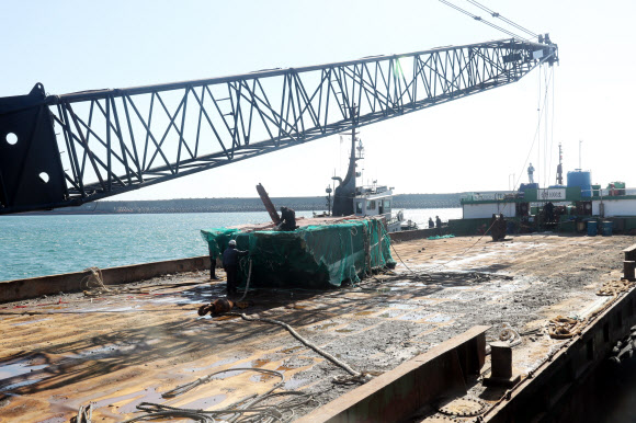 23일 제주시 안덕면 화순항에 도착한 인양 바지선 위에 대성호 선미가 그물에 싸인 채 놓여 있다. 2019.11.23  연합뉴스