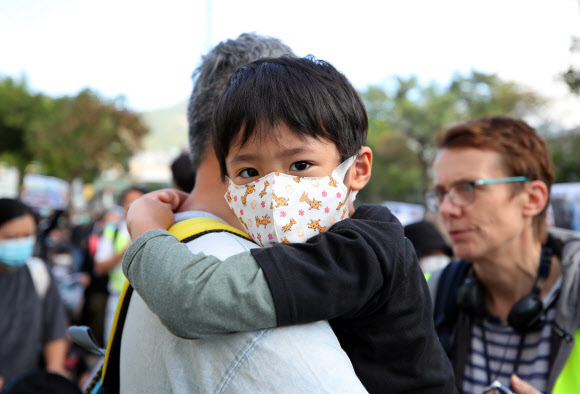 23일 오전 홍콩 카오룽역 인근에서 열린 최루탄 사용 반대 집회에 참가한 한 어린이가 아빠 품에 안겨 행진하고 있다. 2019.11.23  연합뉴스