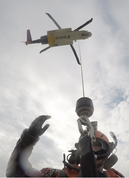항공구조사 심정현 경사가 물보라 치는 바다에서 호이스트를 이용해 익수자를 구조하는 훈련을 하고 있다.
