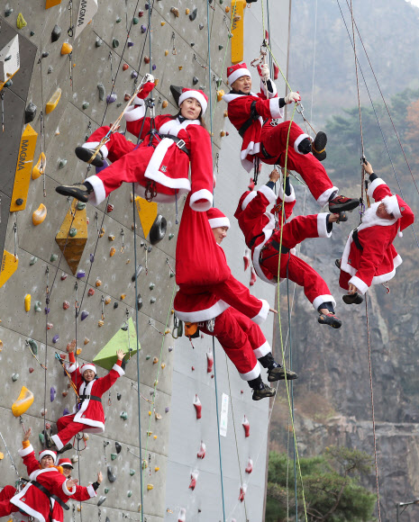 1일 서울 용마산 인공암장에서 열린 구세군 자선냄비 행사 발대식에서 산타복을 입은 암벽 산악회 ‘쌩곰등반클럽’ 회원들이 기념촬영을 위해 줄에 매달려 암벽을 오르고 있다.   박창용 쌩곰등반클럽회장과 산악회원들은 12월 말까지 매주 토, 일요일 8회에 걸쳐 북한산 일대에서 자선모금 캠페인을 할 계획이다. 2019.12.1  연합뉴스