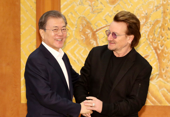 문재인 대통령이 지난해 12월 청와대를 예방한 록밴드 ‘U2’의 보컬이자 사회운동가 보노의 손을 맞잡고 있다. 연합뉴스