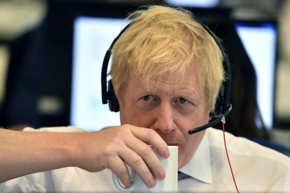 보리스 존슨 영국 총리가 8일(현지시간) 총선을 앞두고 런던에 있는 보수당 선거본부에 마련된 콜센터에서 전화 응대를 하면서 물을 마시고 있다. 런던 AP 연합뉴스