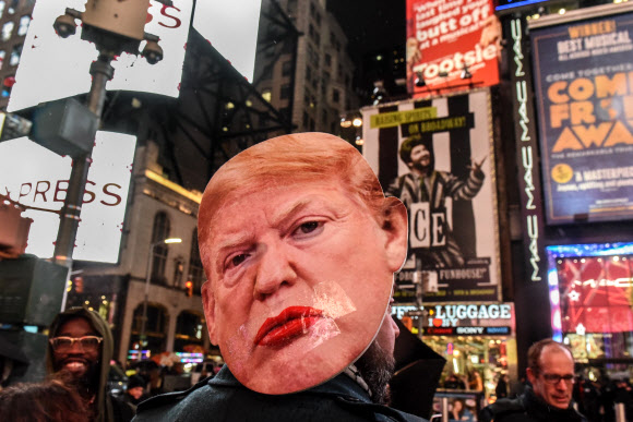 도널드 트럼프 미국 대통령에 대한 하원 탄핵소추안 표결을 하루 앞둔 17일(현지시간) 미국 뉴욕의 타임스 스퀘어에서 탄핵을 지지하는 시위대가 시위를 벌이고 있다. AFP 연합뉴스