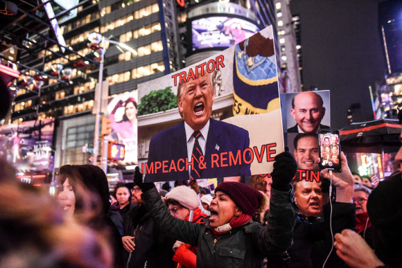 도널드 트럼프 미국 대통령에 대한 하원 탄핵소추안 표결을 하루 앞둔 17일(현지시간) 미국 뉴욕의 타임스 스퀘어에서 탄핵을 지지하는 시위대가 시위를 벌이고 있다. AFP 연합뉴스