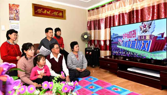 북한 노동당 기관지 노동신문은 21일 “기적을 창조하신 불멸의 업적, 주체108(2019)년 혁명실록을 펼치며”라는 제목으로 ‘3면’에 한 해를 결산하며 김정은 국무위원장을 찬양하는 기사와 사진을 보도했다. 사진은 북한의 한 가정집에서 조선중앙TV를 시청하고 있는 모습. 한 남성은 노동신문을 들고 있다.  평양 노동신문=뉴스1
