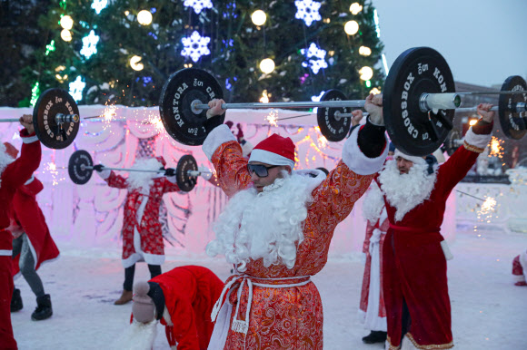 프로스트 신부 복장을 한 사람들이 20일(현지시간) 러시아 티트랄리 광장에서 열린 크리스마스 트리 행사중 바벨을 들어올리고 있다. 타스 연합뉴스