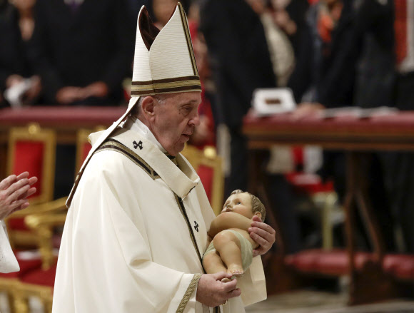 프란치스코 교황이 24일(현지시간) 바티칸 성베드로대성당에서 성탄 전야 미사를 마친 후 아기 예수 조각상을 들고 걸어가고 있다. AP 연합뉴스