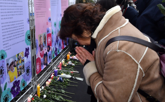 25일 2019년 마지막으로 열린 수요집회에 참석한 시민들이 2019년 한해 사망한 위안부 피해자 할머니들을 기리는 추모판 앞에서 헌화 추모를 하고 있다. 2019.12.25 <br>박지환 기자 popocar@seoul.co.kr