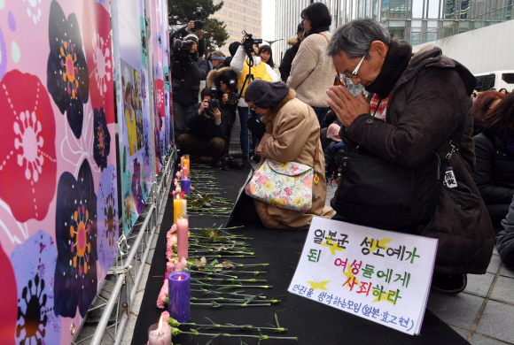 성탄절인 25일 올해 마지막으로 열린 수요집회에 참석한 시민들이 올 초 별세한 일본군 성노예제 피해 할머니 5명의 생애를 소개한 전시물 앞에서 헌화하며 추모하고 있다. 박지환 기자 popocar@seoul.co.kr