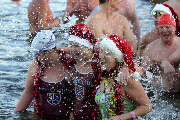 서펜틴 수영 클럽의 수영선수들이 25일(현지시간) 영국 런던 중심부 하이드 파크에서 매년 크리스마스 날 세펜틴에서 열리는 ‘피터 팬 컵 경주(the Peter Pan Cup race)’에 참가해 환호하고 있다. AP 연합뉴스