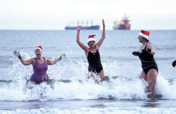 킹 에드워드 베이 수영선수들이 25일(현지시간) 영국 뉴캐슬의 킹 에드워드 베이에서 해가 떴을때 크리스마스 날 맞이 입수를 즐기고 있다. AP 연합뉴스