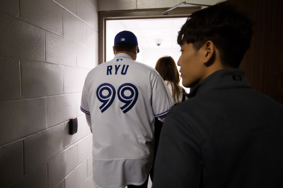 류현진이 27일(현지시간) 캐나다 온타리오주 토론토에서 열린 미국프로야구 토론토 블루제이스 입단식 후, 아내 배지현 씨와 함께 자신의 이름과 등번호가 새겨진 유니폼을 입고 이동하고 있다. AP 연합뉴스