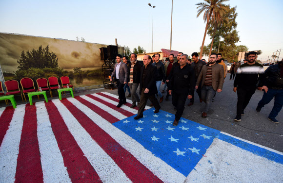 이라크 바그다드에서 시아파 무장단체 지지자들이 도로에 미국 국기를 그려넣고 이를 밟으며 지나가고 있다. 바그다드 AFP연합뉴스 자료사진