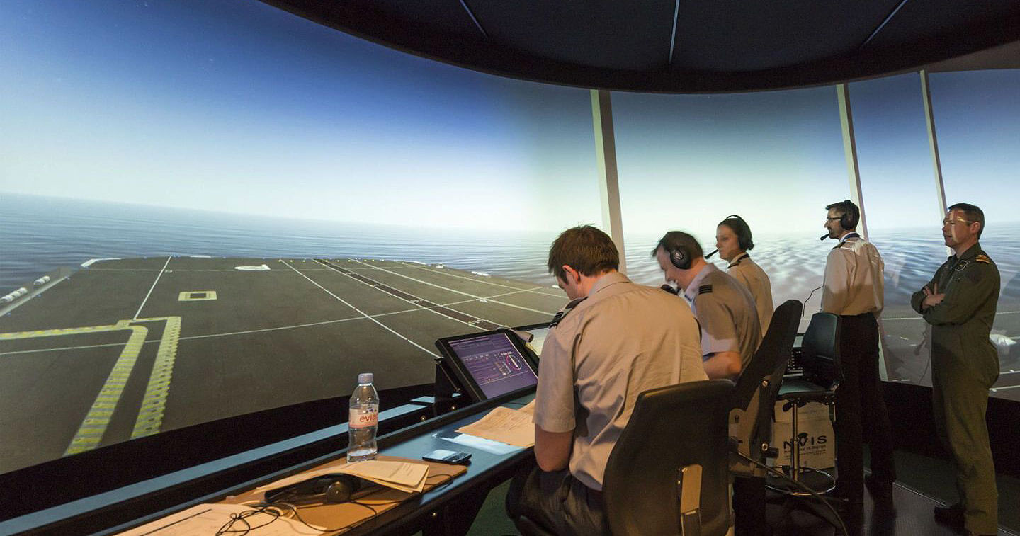 F-35 QEC 통합 시뮬레이터를 활용해 함교에서 대형 스크린으로 F-35 착륙 통제를 하는 착륙 안전 담당관들. BAE 시스템즈 제공