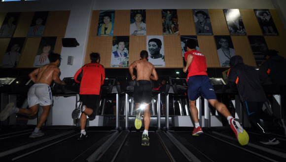 역대 금메달리스트들의 사진이 벽에 붙어 있는 진천선수촌 체력단련장에서 국가대표 선수들이 구슬땀을 흘리며 달리고 있다.