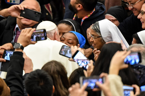 프란치스코(왼쪽 뒷모습) 교황이 8일(현지시간) 바티칸 성베드로성당에서 순례를 온 수녀의 요청을 받고 볼에 입을 맞추고 있다. 바티칸 AFP 연합뉴스