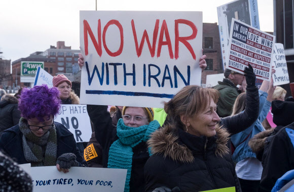 지난 9일(현지시간) 도널드 트럼프 미국 대통령의 올해 첫 대선 집회가 열린 오하이오주 털리도의 헌팅턴 센터 앞에서 시위대가 ‘이란과의 전쟁 반대’를 외치며 피켓을 들어 보이고 있다. 털리도 AFP 연합뉴스