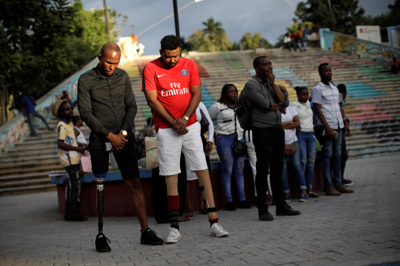 Two men who were wounded during 2010 earthquake, observe a minute of silence during commemorations for the tenth anniversary of the quake in Port-au-Prince