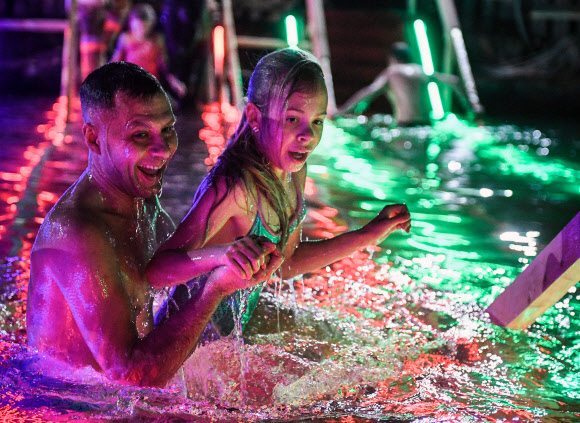 19일(현지시간) 정교회 신도들이 러시아 모스크바에서 공현 대축일을 맞아 얼음물 속으로 뛰어들고 있다. AFP 연합뉴스